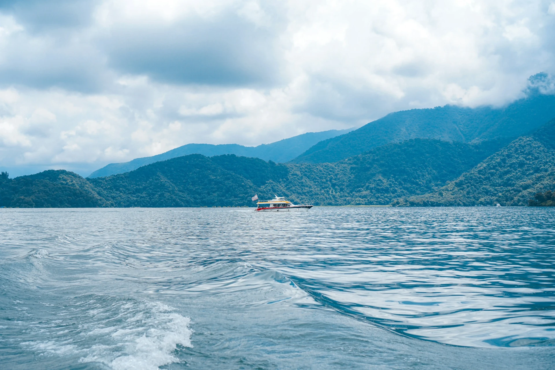 日月潭湖面遊船航行，群山環繞的湖景風光